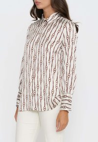 Langarm-Hemd in Creme mit braunem Kettenmuster, ausgestattet mit einem klassischen Kragen und geradem Saum, aus glattem Stoff gefertigt.