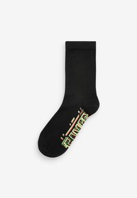 Chaussette noire en tissu lisse, présentant un design graphique coloré en vert, rouge et blanc près de la cheville.