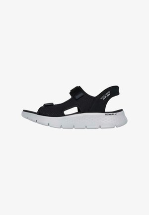 Black athletic sandal with open design, adjustable straps, cushioned white sole, and perforated upper for breathability. Notable “Go Walk” branding.