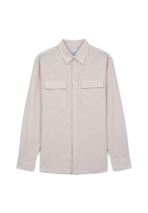 Chemise à manches longues couleur beige clair, avec un col, deux poches avant et des boutons. Tissu doux avec une texture subtile.