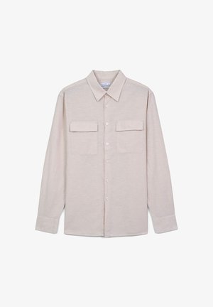 Chemise à manches longues couleur beige clair, avec un col, deux poches avant et des boutons. Tissu doux avec une texture subtile.