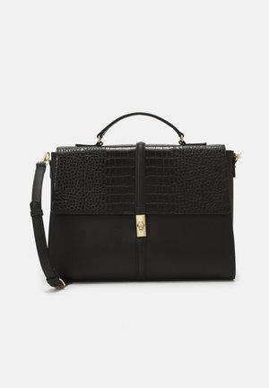 Sac à main noir présentant une texture embossée croco brillante sur le rabat, un corps lisse, des accessoires dorés et une bandoulière amovible.