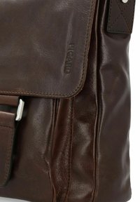 Bruine leren schoudertas met een gladde textuur, klep sluiting en reliëf logo detail. Inclusief een slanke accenten van zilver hardware.