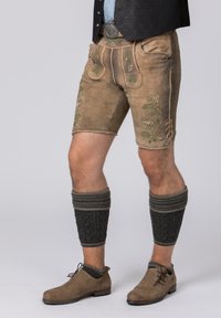Brown leather shorts with green floral embroidery, paired with textured black leg warmers and tan shoes. Classic Bavarian design elements.