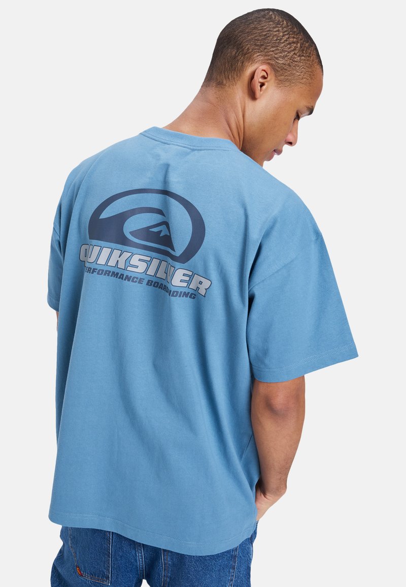 Blå bomull t-skjorte med løs passform, med en stor mørkeblå Quiksilver-logo på baksiden og korte ermer.