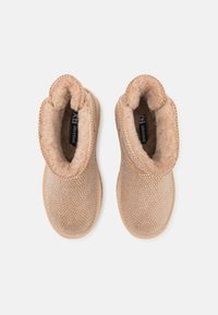 Botas cortas beige con un forro de piel sintética texturizada y un patrón metálico de puntos. Diseño de punta redonda y tacón bajo.