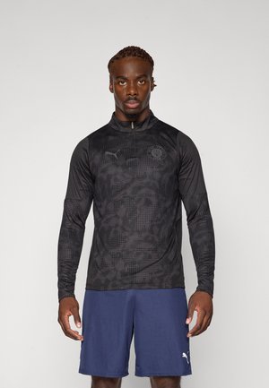 Black long-sleeve athletic top with a half-zip, textured pattern, and Puma logo on the chest. Paired with blue shorts, featuring a white logo.