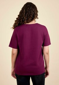 Bordeaux kortemouwen T-shirt met een ronde hals en een losse pasvorm. Zachte katoenen stof met een gladde textuur. Achteraanzicht weergegeven.