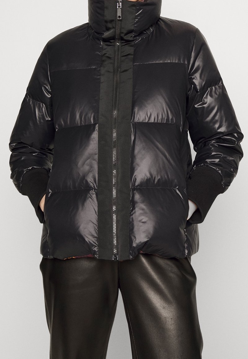 Doudoune noire avec col montant, dotée d'une fermeture éclair frontale et de panneaux texturés. Fabriquée en matériau brillant ; comprend des poignets côtelés.