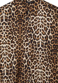 Camicia a maniche lunghe con stampa leopardata, colletto a punta e bottoni neri al centro.