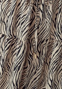 Viegls, rakstains audums ar bēša krāsas fonu un izteiksmīgām melnām zebras svītrām. Regulējams aukliņu dizains ar zelta akcentiem.