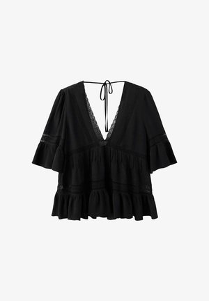 Blouse noire ample avec col en V profond, bordure en dentelle, manches évasées jusqu’au coude, ourlet à volants et fermeture à nouer au niveau de l’encolure arrière.