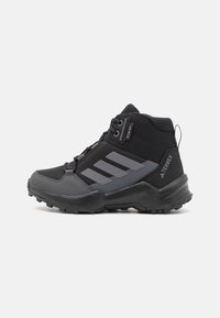 Black high-top hiking shoe with mesh and synthetic material, featuring gray accents, three-stripe logo, and rugged rubber sole for traction.