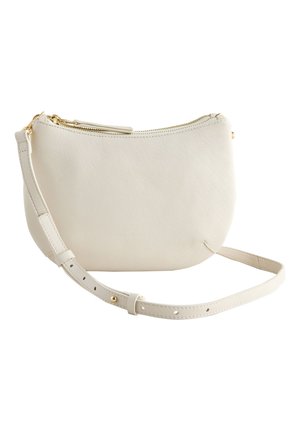 Lille off-white læder crossbody taske med gyldent lynlås og justerbar rem på hvid baggrund.