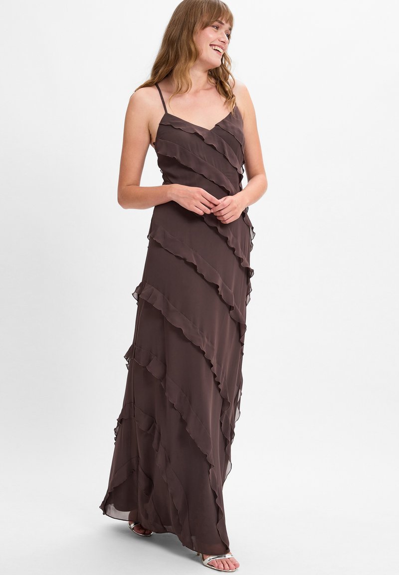 Langes, braunes, ärmelloses Kleid aus fließendem Stoff mit gestuften Rüschen. Das Kleid hat ein V-Ausschnitt-Design und reicht bis zum Boden.