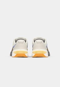 Gray and beige athletic shoes with a textured upper, blue accents, and a white, orange outsole feature a cushioned collar and logo.