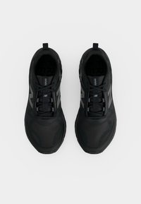 Ζευγάρι μαύρα αθλητικά παπούτσια New Balance με κορδόνια, φαίνονται από ψηλά σε λευκό φόντο.
