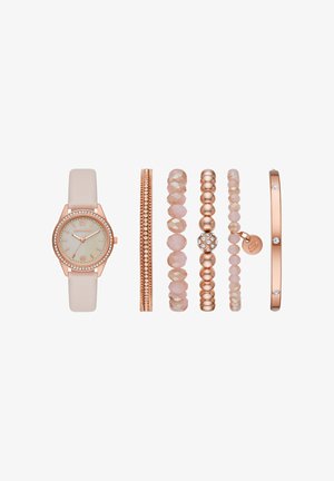Montre en or rose avec un bracelet beige et cinq bracelets coordonnés en or rose, perles roses et métal, disposés côte à côte sur fond blanc.