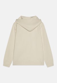Beige kapucnis pulóver puha textúrával, nagyméretű kapucnival, bordázott mandzsettákkal és aljjal. A hátsó oldalán nincs látható logó vagy minta.