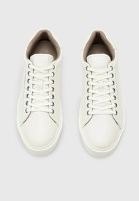 Sneaker in pelle bianca con una superficie liscia, punta rotonda e fodera in tessuto. Presenta occhielli metallici e chiusura con lacci piatti.