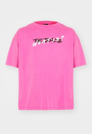 Bright pink short-sleeve T-shirt made of soft fabric. Features a graphic print in black and white text across the front that reads "WHAT IS?"