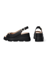 Černé slingback sandály na klínku s texturovaným svrškem, otevřenou špičkou a dekorační přezkou. Mají masivní, kontrastní podrážku.