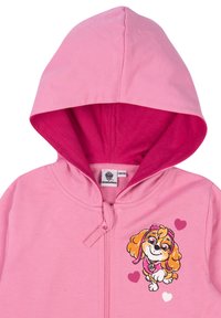 Felpa con cappuccio rosa caratterizzata da una grafica di un cane cartone animato, con un esterno di un rosa chiaro e una fodera di un rosa più scuro, chiusa con una zip frontale.