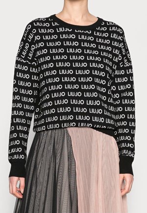 Schwarzer Langarmpullover mit wiederholtem weißen "LIU JO" Schriftzug, kombiniert mit einem plissierten Rock in abwechselnden schwarzen und hellrosa Paneelen.