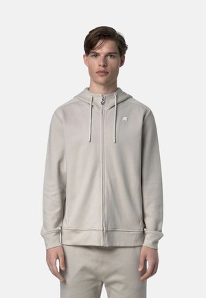 Felpa grigia chiara con zip, cappuccio e lacci, caratterizzata da un logo discreto sul petto e polsini e orlo a coste. Texture del tessuto morbida.