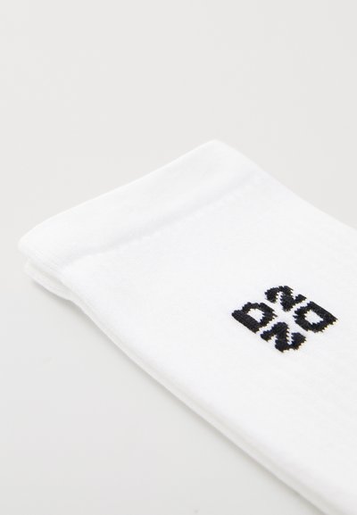 White cotton sock with a ribbed cuff featuring a black graphic design. The texture is smooth, with a clean, minimalist appearance.