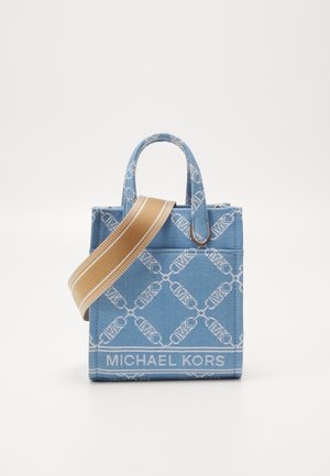 Bolso tote azul de Michael Kors con patrón de logotipo blanco, dos asas superiores y una amplia correa para el hombro beige cruzada en la parte delantera.