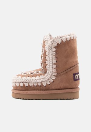 Bottine en suede marron avec des coutures blanches décoratives, un accent tressé et une semelle texturée pour la stabilité et l'adhérence.