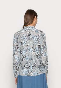 Camicetta a maniche lunghe in tessuto leggero con motivo floreale in tonalità di blu e nero, caratterizzata da un colletto arricciato e un dettaglio sul retro arricciato.