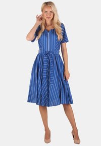 Blau gestreiftes Kleid mit kurzen Ärmeln, V-Ausschnitt und tailliertem Bund. Der Stoff wirkt glatt und leicht und reicht bis zur Mitte der Wade.