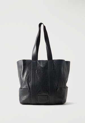 Black textured leather tote bag with two long handles and a small front patch pocket on a white background.