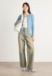 Light blue knitted cardigan with cable pattern, white top, wide-leg faded denim pants, and light blue heeled sandals. Beige handbag.