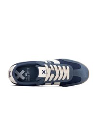 Zapatilla de color azul marino con acentos blancos, materiales de ante texturizado y malla, con punta redonda, cordones planos y logotipo en la lengüeta.