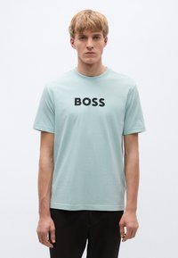 Hele-sinine lühikeste varrukatega puuvillane t-särk, mille rinnal on julge must "BOSS" logo. Lihtne ja klassikaline disain.