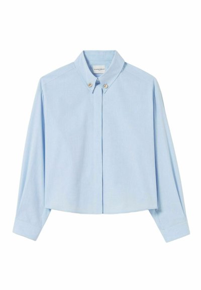 Chemise courte bleu clair à manches longues, avec un col boutonné et deux boutons décoratifs sur le devant, fabriquée à partir d'un tissu lisse.