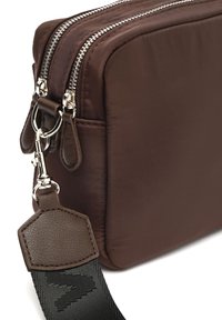 Borsa a tracolla in nylon marrone con doppia chiusura a zip, dettagli in pelle e tracolla testurizzata. Caratterizzata da una forma rettangolare compatta.