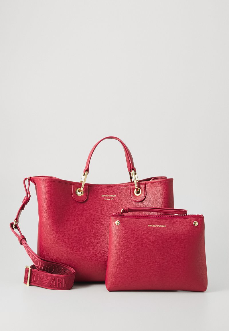 Red leather handbag with gold hardware, featuring two handles, removable shoulder strap, and a small matching pouch with a zipper.