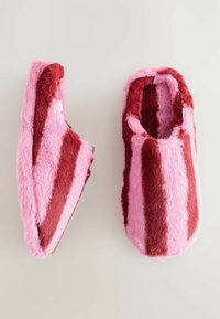Villahuopaslämpöiset tossut, joissa on vuorotellen punaisia ja vaaleanpunaisia raitoja, pehmeä tekstuuri, pyöreä muoto ja avoin takakappale, joka mahdollistaa helpon pukemisen.