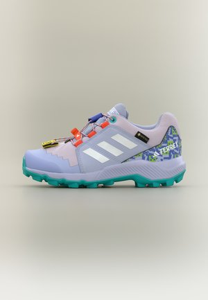 Chaussure de randonnée Adidas Terrex couleur violet clair avec semelle turquoise, bandes blanches, talon camouflage numérique et œillets de lacets orange sur un fond uni.