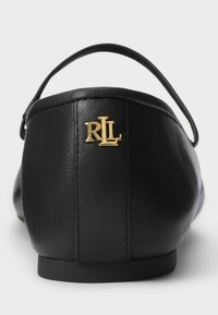 Čierne kožené ploché topánky z pohľadu zozadu s tenkým remienkom a zlatým logom "RLL" na päte.