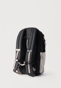 Μαύρο και γκρι σακίδιο Columbia με επενδεδυμένους ιμάντες, κούμπωμα στο στήθος και πλαϊνές τσέπες, εμφανίζεται όρθιο σε απλό φόντο.