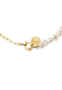 Pulsera de cadena de oro con perlas blancas irregulares, un cierre redondo y un charm con logo de borde texturizado.
