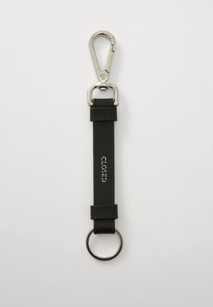 Sort lærnøkkelring med sølvmetallklips, sirkulær ring og preget "CLOSED"-tekst på reimen. Glatt tekstur, minimalistisk design.