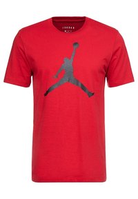 Camiseta de algodón roja con cuello redondo. Presenta un gran logo negro de Jumpman en el centro, mostrando una icónica pose de baloncesto.