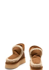 Stivali alla caviglia marroni con un interno morbido, caratterizzati da un bordo testurizzato e cucito e una suola a piattaforma spessa e di colore chiaro.