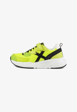 Neon green athletic shoe with mesh upper, black accents, adjustable strap, and white sole. Features a textured finish and contrasting design.